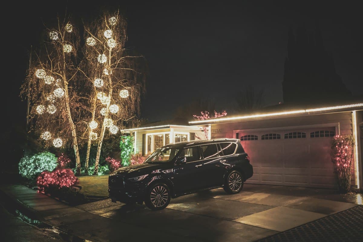 A Kendall-style residential street at night with homes decorated in Christmas lights