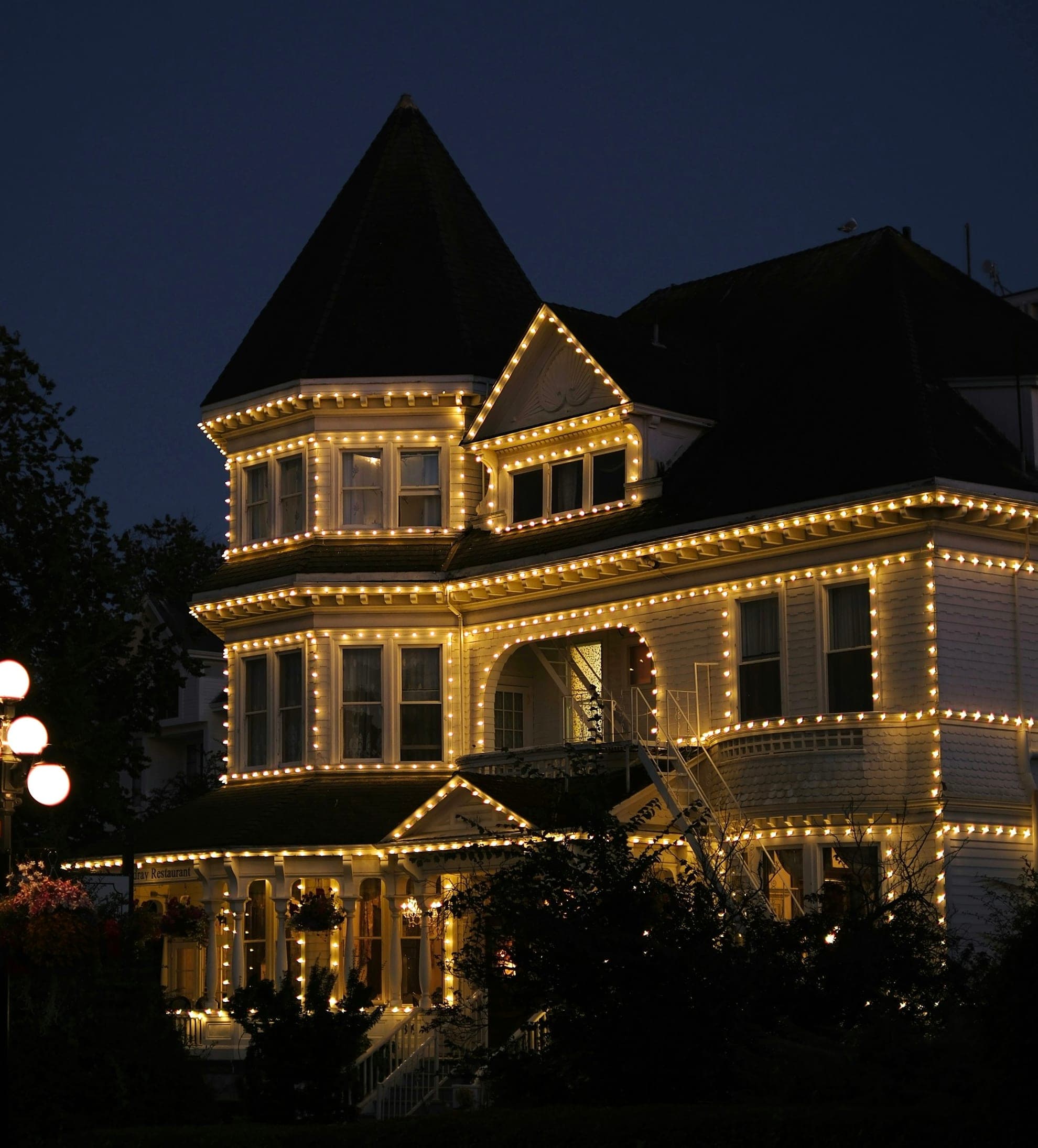 Warm white C9 Christmas lights along a home's roofline eaves at night